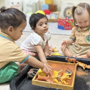 Children exploring a sensory tray together on the floor