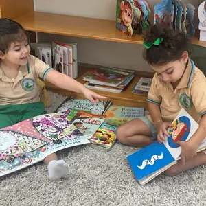 Two children looking at a picture book on the carpet