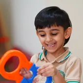 A smiling boy holding a wooden play tool
