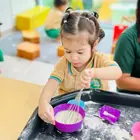 A child scooping foam in a sensory tray
