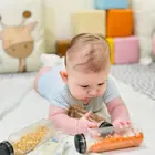 A baby exploring a sensory bottle on the floor