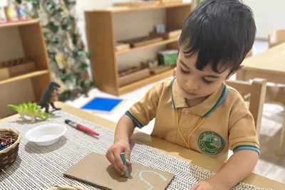 A child working with wooden letters and baskets on a Montessori shelf-lined classroom table